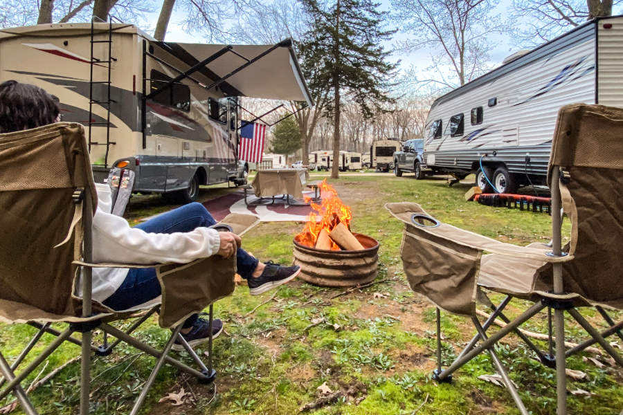 woman sitting by fire outside of camper
