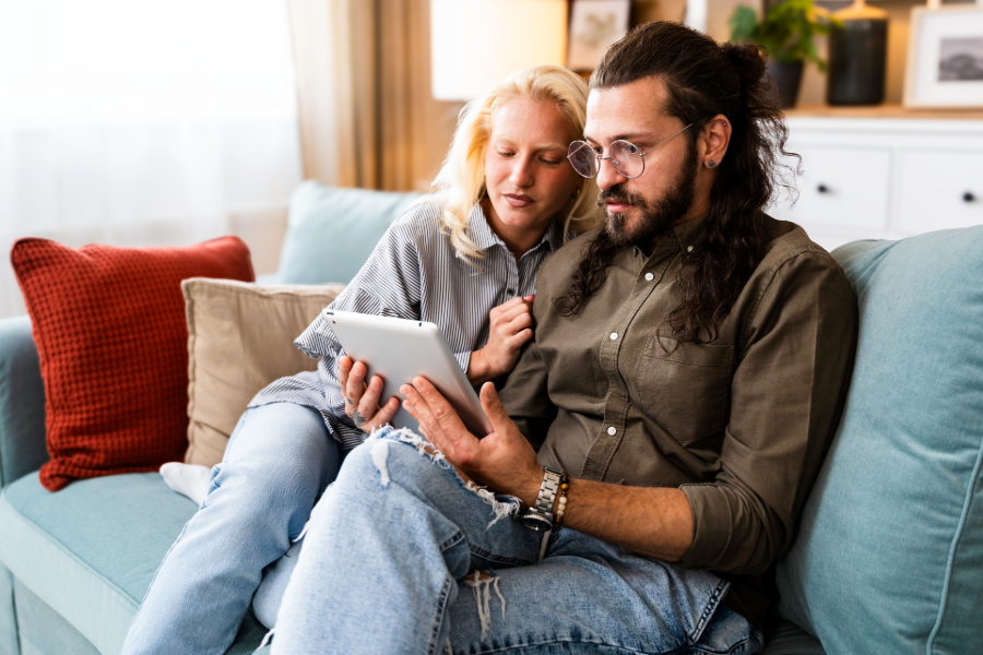 wan and woman cuddling on couch looking at tablet